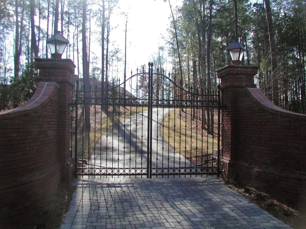 A large black wrought iron gate with brick pillars and lanterns installed by United Fence Company in Johnston, RI.