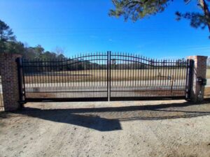 A large black wrought iron style gate with brick pillars installed by JB Nealy Fence in Elgin, SC.