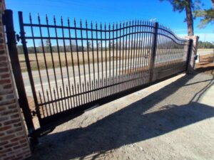 A large black wrought iron style sliding gate with brick pillars installed by JB Nealy Fence in Elgin, SC.