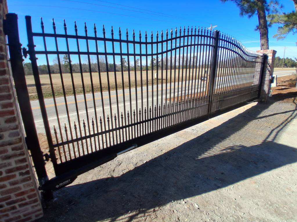 A large black wrought iron style sliding gate with brick pillars installed by JB Nealy Fence in Elgin, SC.