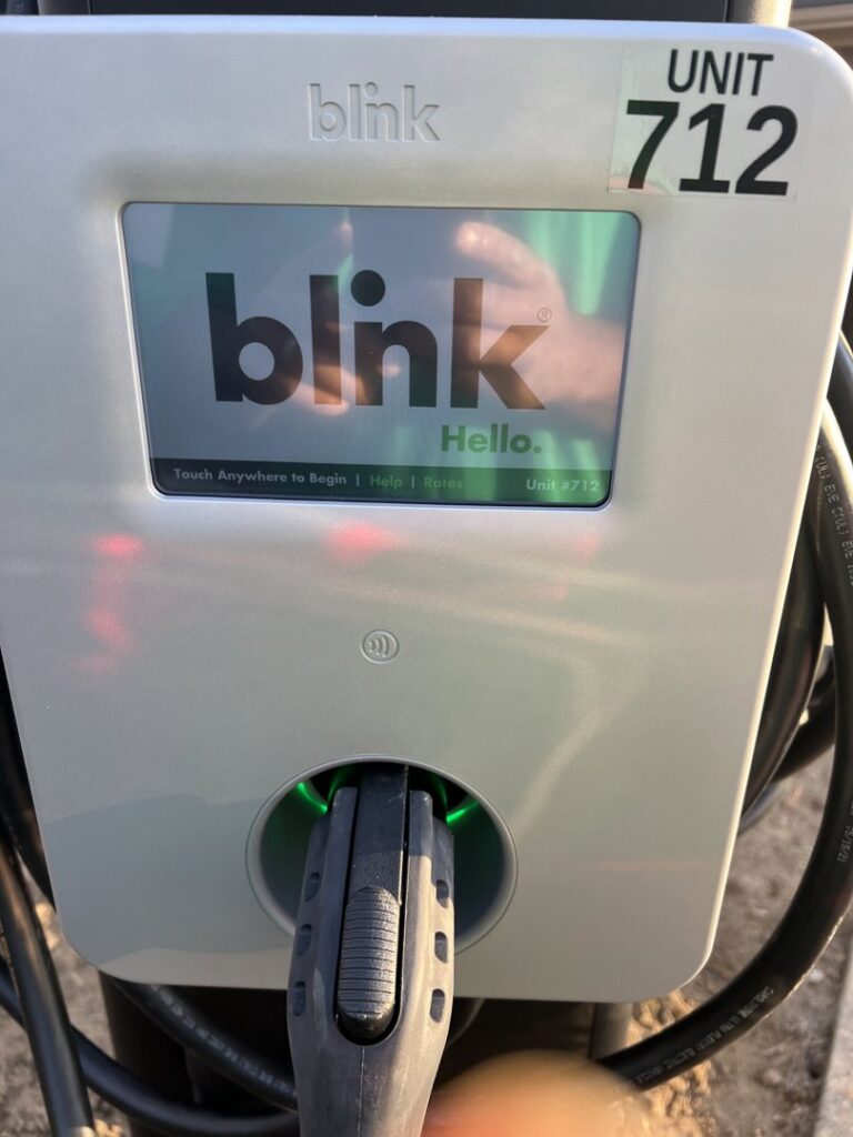 A Blink EV charger displaying 'Hello' on its screen, indicating it's ready for use, installed by Green Volt Electric LLC in Durham, NC.