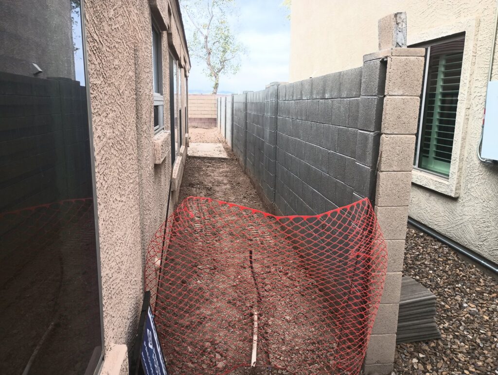 A block wall fence under construction with orange safety netting by Arce Masonry LLC in Glendale, AZ