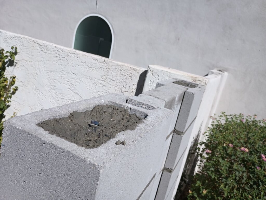 The top of a block wall fence being filled with concrete during construction by Arce Masonry LLC in Glendale, AZ