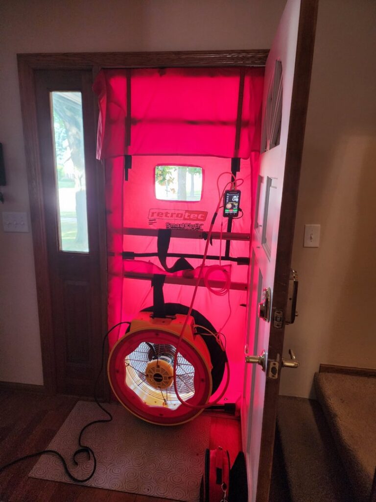 A blower door test setup in a doorway, used for energy audits and air leakage testing by Evergreen HVAC Comfort Solutions in Milwaukee, WI.