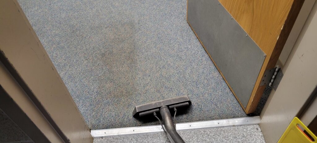 A carpet cleaning wand cleaning a blue carpet in a doorway by Ardent Carpet Restore in Sacramento, CA.