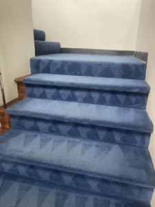 A blue carpeted staircase showing distinct cleaning patterns after a professional service by Capital City Floor Care LLC in Columbus, OH.