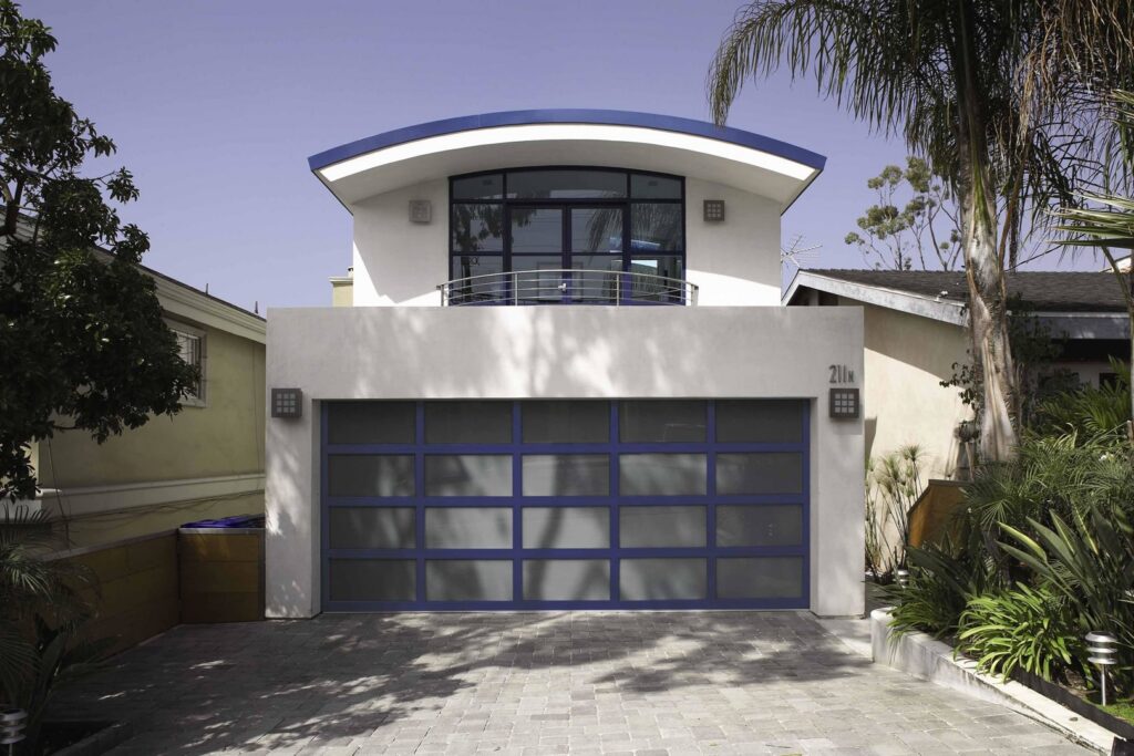A blue-framed frosted glass garage door installed on a modern home by Overhead Door Company of Salem in Salem, OR.