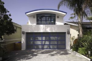 A blue-framed frosted glass garage door installed on a modern home by Overhead Door Company of Salem in Salem, OR.