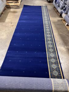 A large roll of blue patterned carpet partially unrolled, showcasing product from Musalla Masjid Carpets in Glendale Heights, IL.