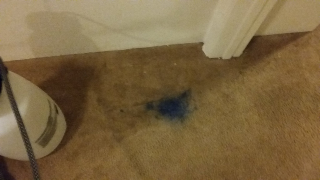 A close-up of a blue stain on a brown carpet, indicating a cleaning challenge for Oahu Carpet Cleaning Co. in Honolulu, HI.