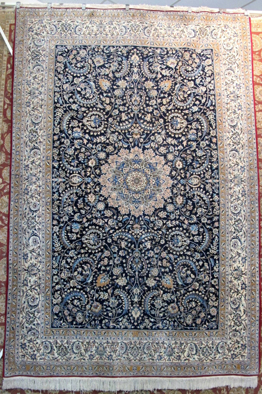 A blue and white oriental rug with a large central medallion and floral designs from Iowa Oriental Rug Co in Davenport, IA.