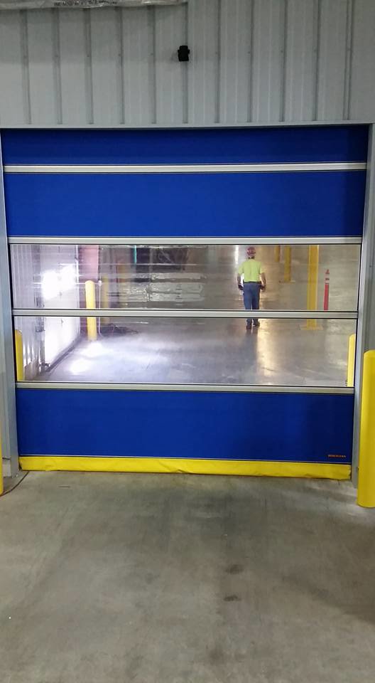 A blue and yellow high-speed commercial roll-up door with clear panels, installed by Tri County Overhead Door Service Inc in New London, WI