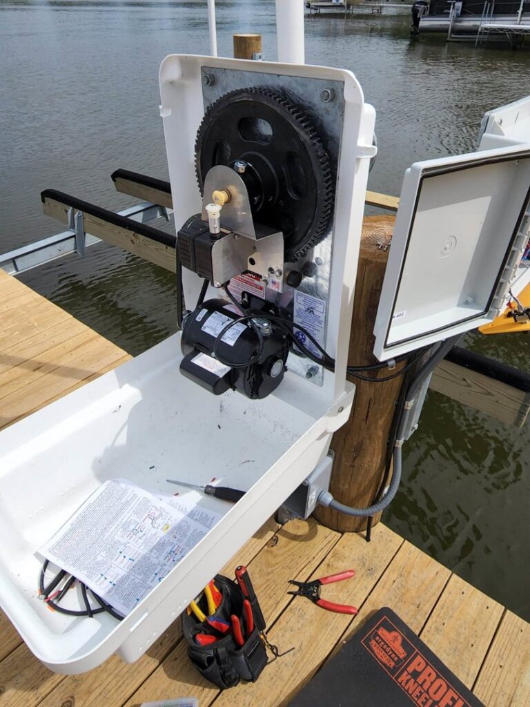 An electrician working on a boat lift motor and control box by the lake, performed by Apparent Electric LLC in Oshkosh, WI.