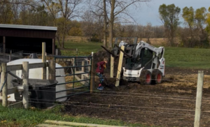 A Bobcat machine and a child near a fence and gate, showing fence installation or repair by Boundary Line- Fencing Solutions in Long Lake, MN.
