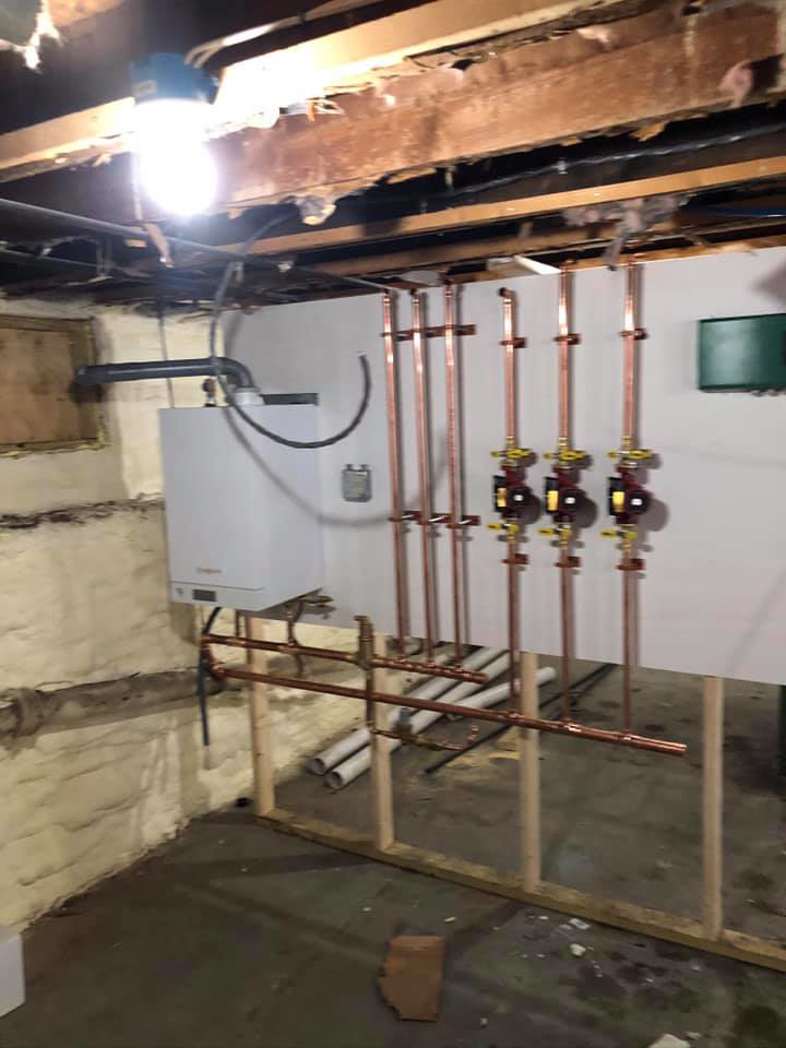 Boiler unit with vertical copper piping and valves installed by Ausoli Grace Plumbing & Hvac in South Portland, ME.