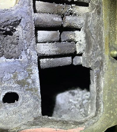 Close-up of a boiler combustion chamber showing soot and debris, serviced by Q1 Mechanical Services, LLC in Wasilla, AK