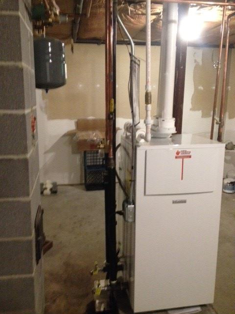 A newly installed boiler or furnace with piping in a basement by Maine Heating Solutions in South Portland, ME.