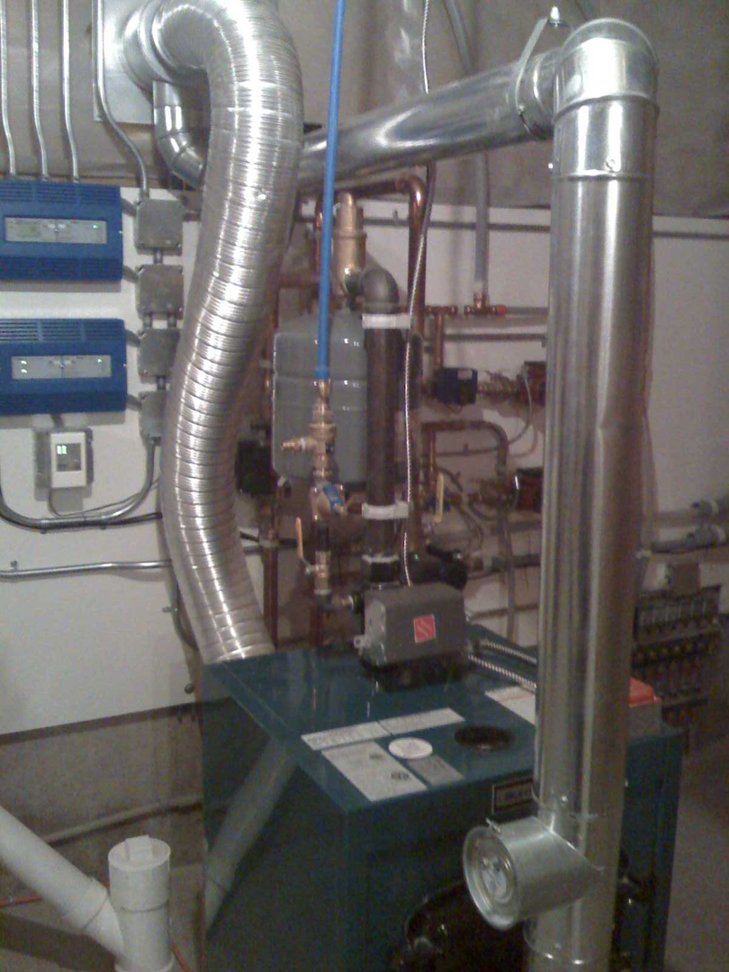 A newly installed boiler or furnace system with extensive ductwork by Versatile Services in Auburn, ME.