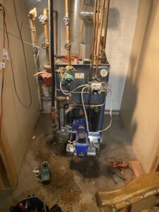 An indoor boiler or furnace system being serviced with tools on the floor by Kane Heating & Air in Mountain Top, PA.