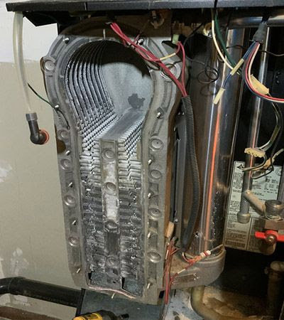 Internal view of a boiler heat exchanger showing scale buildup, serviced by Q1 Mechanical Services, LLC in Wasilla, AK