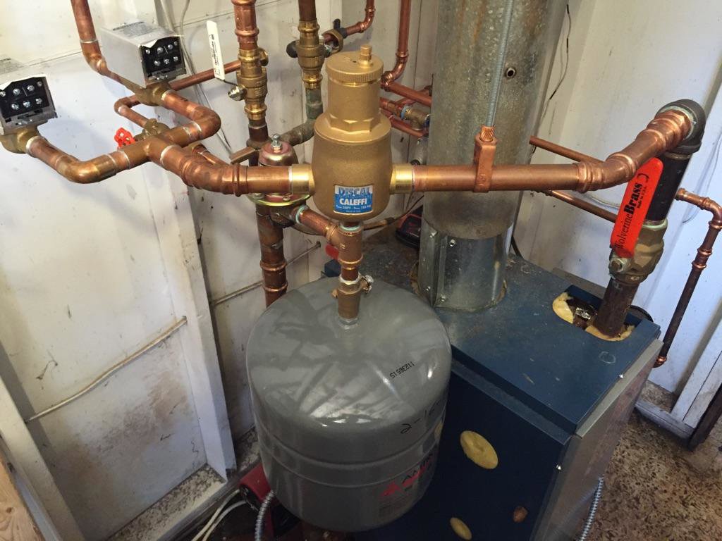 Complex copper piping, valves, and an expansion tank connected to a boiler heating system by David J. Winston Co. in Erie, PA.