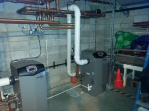 Two large boilers with complex piping installed in a utility room by Action Mechanical LLC in Eau Claire, WI.