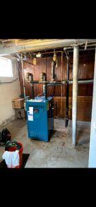 A blue boiler system with associated piping and controls installed in a basement by Evergreen HVAC Comfort Solutions in Milwaukee, WI.
