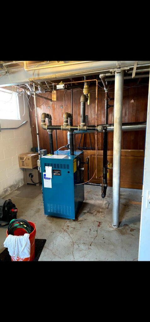A blue boiler system with associated piping and controls installed in a basement by Evergreen HVAC Comfort Solutions in Milwaukee, WI.