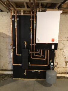 A modern boiler system with copper piping professionally installed in a basement by Garrison City HVACR in Dover, NH