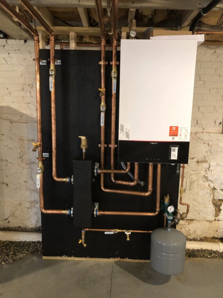 A modern boiler system with copper piping professionally installed in a basement by Garrison City HVACR in Dover, NH