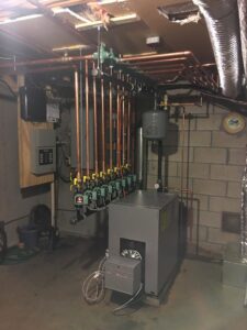 A boiler system with a complex copper piping manifold and expansion tank installed by Nate's Oil Burner Service in New Bedford, MA