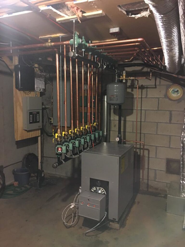 A boiler system with a complex copper piping manifold and expansion tank installed by Nate's Oil Burner Service in New Bedford, MA
