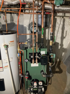 A boiler and water heater installation with extensive piping in a basement by New Yorker Boiler in Lancaster, PA
