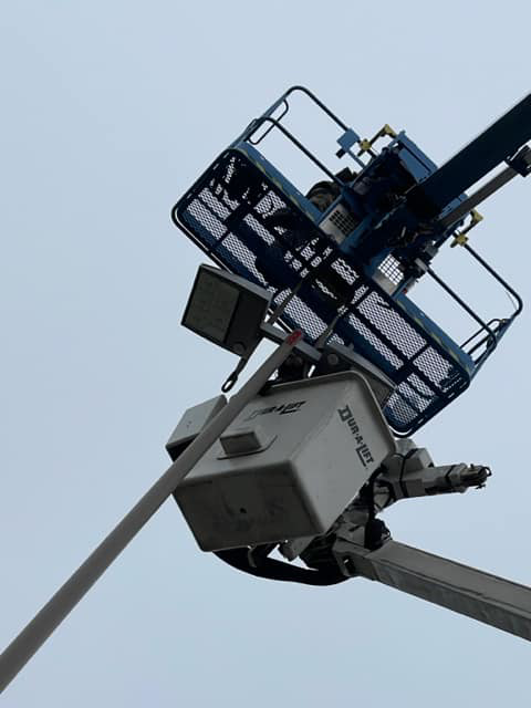 A boom lift bucket positioned to service a light fixture on a tall pole by Lighting Services, Inc. in Waterbury, CT.