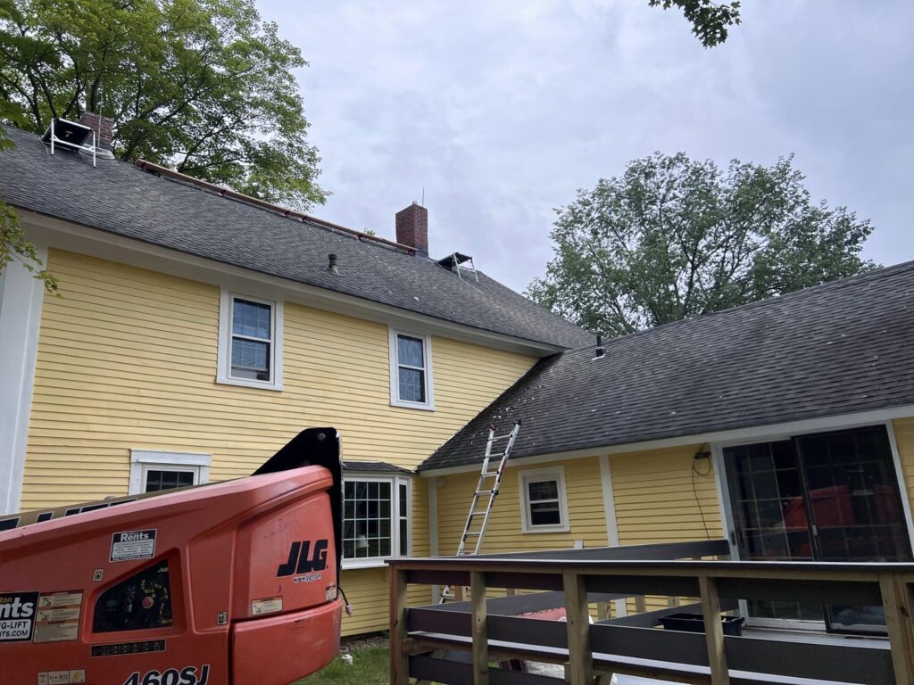 A boom lift and ladders set up for chimney or roof work on a house by Granite State Chimney in Manchester, NH