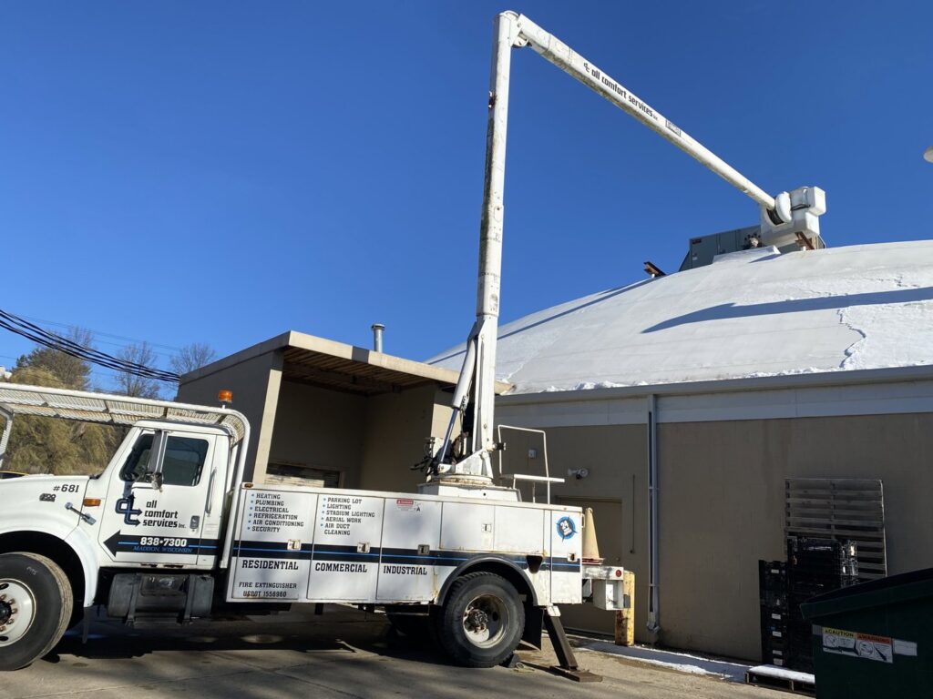 A boom lift truck from All Comfort Services positioned for rooftop HVAC unit service in Madison, WI
