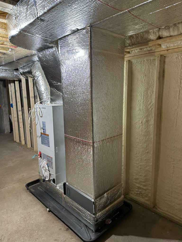 A newly installed Bosch HVAC unit with insulated ductwork in a basement by Massachusetts Pro HVAC in Shrewsbury, MA.