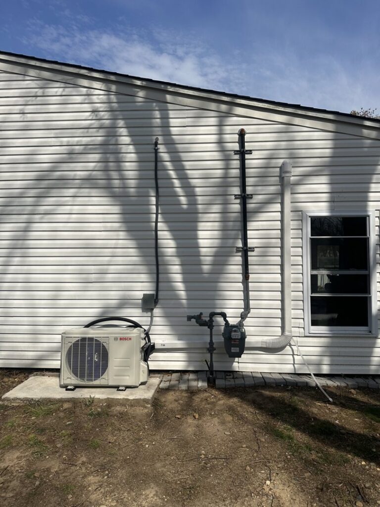 An outdoor Bosch mini-split condenser unit professionally installed next to a residential building by Indoor Expert Heating & Cooling in Paterson, NJ.