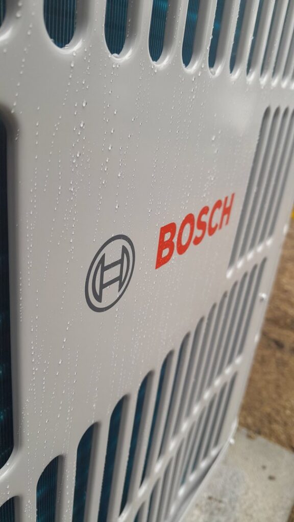 A close-up view of a Bosch outdoor air conditioning unit with water droplets, installed by PNW Spokane Heating and Air in Spokane, WA.