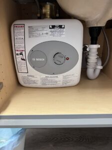 A Bosch instant hot water heater installed under a sink, a service provided by Quistian Lighting in Arlington, TX