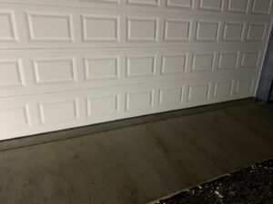A close-up of the bottom panel and weather seal of a white garage door, installed or repaired by Affordable Overhead Garage Door in Modesto, CA