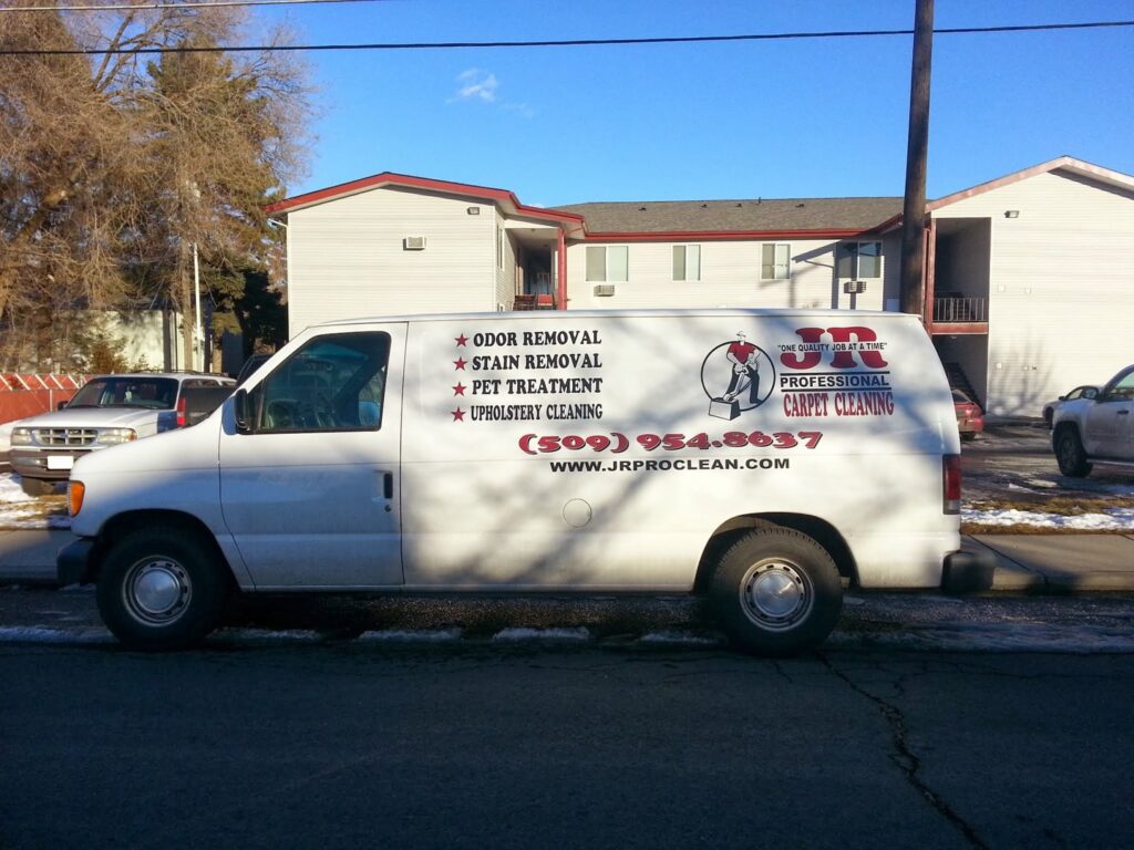 A branded white van for JR Professional Carpet Cleaning Business LLC, showcasing services, parked on a street in Spokane, WA.