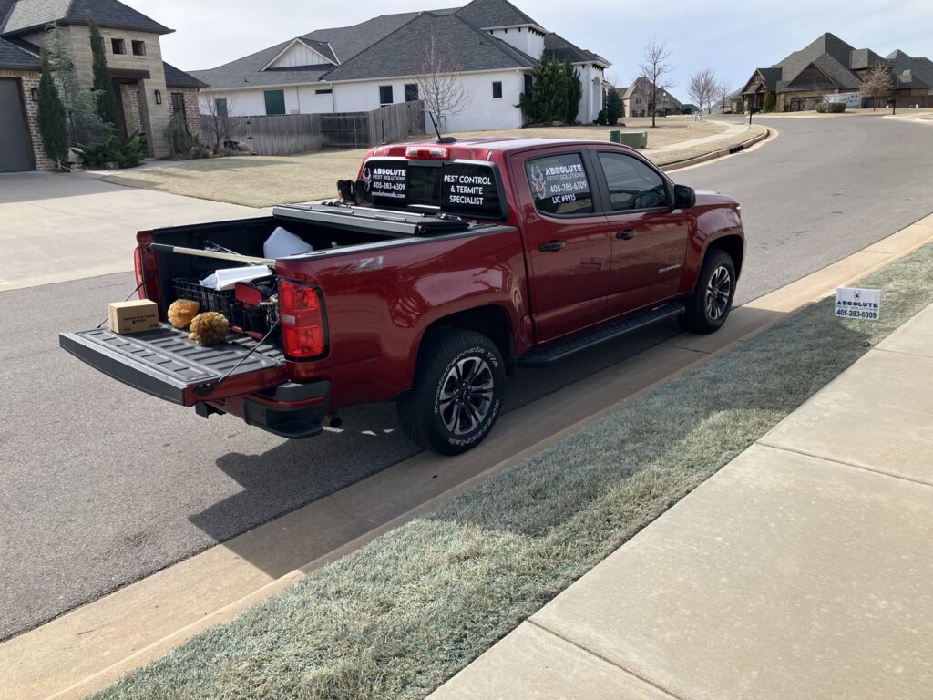 An Absolute Pest Solutions branded service truck with equipment in the bed, parked on a residential street in Piedmont, OK.