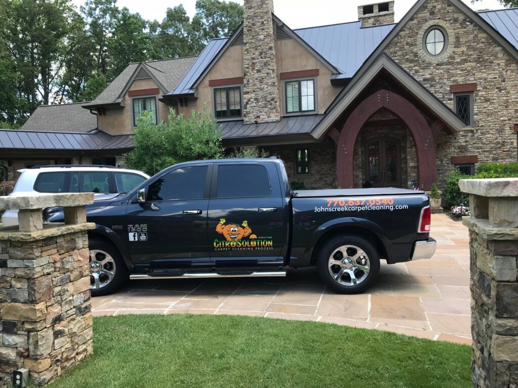 A branded Johns Creek Carpet Cleaner service truck parked at a residential job site in Johns Creek, GA.