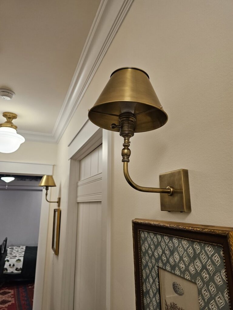 Brass wall sconces and a ceiling light fixture installed in a hallway by Powered Electrical & Lighting Services LLC in Springfield, MO.