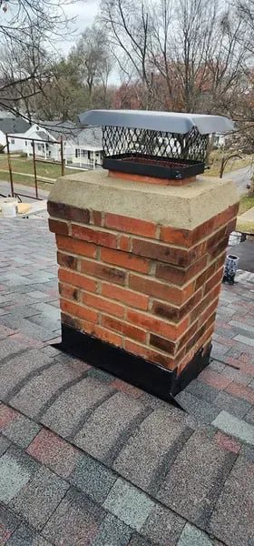 A well-maintained brick chimney with a metal cap on a residential roof, a completed service by The Chimney Doctor in Louisville, KY.