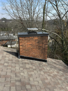 A brick chimney with a new cap installed on a residential roof by Soot Busters in Birmingham, AL.