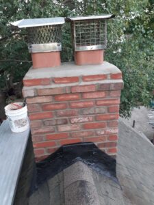 A brick chimney with newly installed chimney caps and flashing, demonstrating a completed job by Colombus Chimney in Elizabeth, NJ.