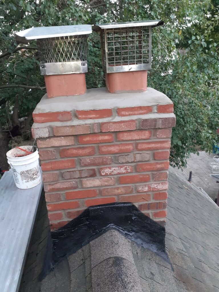 A brick chimney with newly installed chimney caps and flashing, demonstrating a completed job by Colombus Chimney in Elizabeth, NJ.