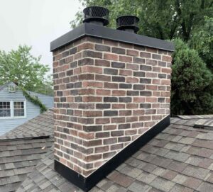 A well-maintained brick chimney with two new chimney caps on a residential roof, showcasing work by Charmed Chimney Service in Baltimore, MD.